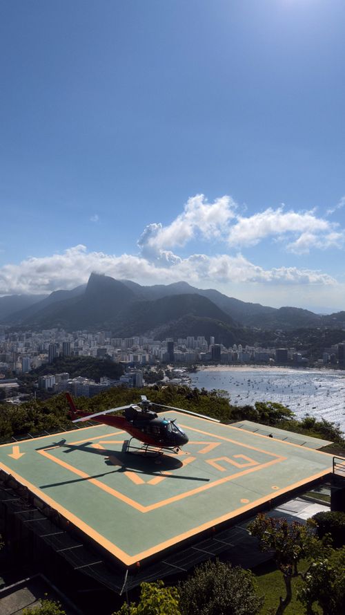 Free A helicopter rests on a helipad with a stunning view of Rio de Janeiro's skyline and mountains. Stock Photo