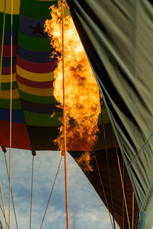 Free Close-up of a hot air balloon with flames soaring during inflation against a blue sky. Stock Photo