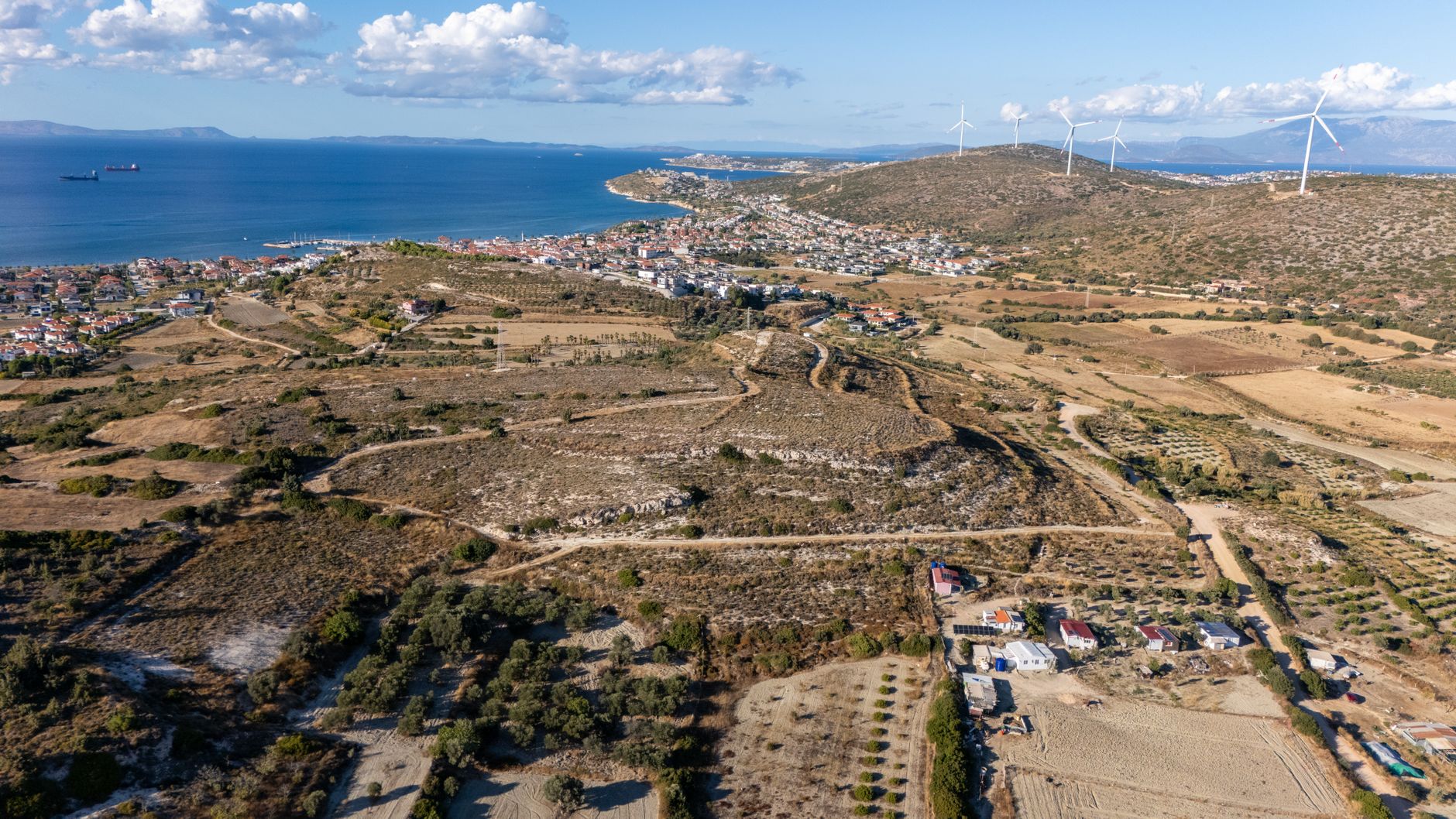 A breathtaking aerial view of a coastal town with wind turbines in the distance, capturing the essence of summer tranquility.