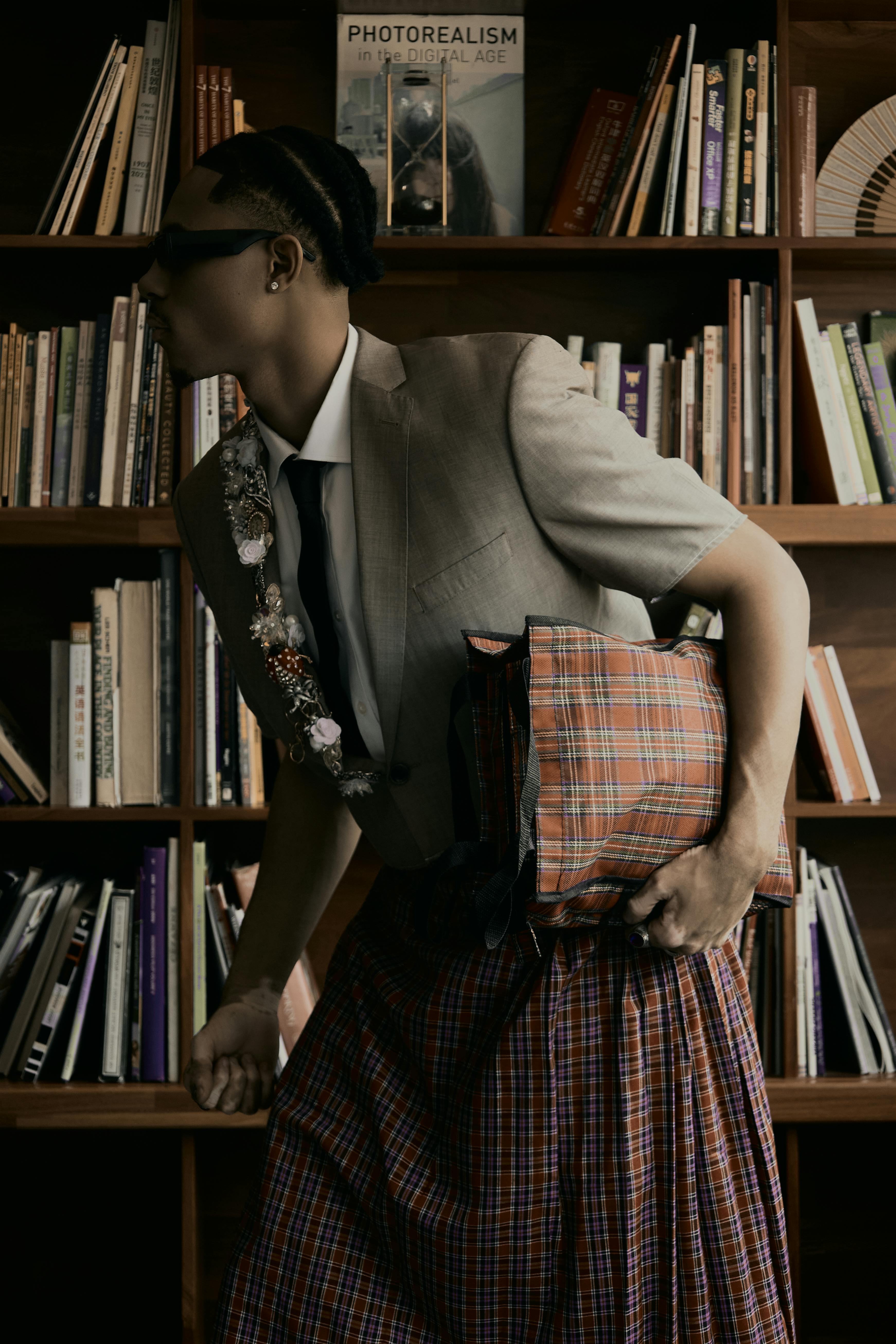 Trendy person holding a plaid bag in a library. Unique fashion sense captured indoors.