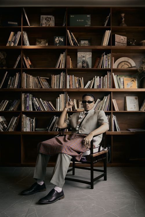 Free A sophisticated man in a library setting, sitting elegantly in front of a bookcase. Stock Photo