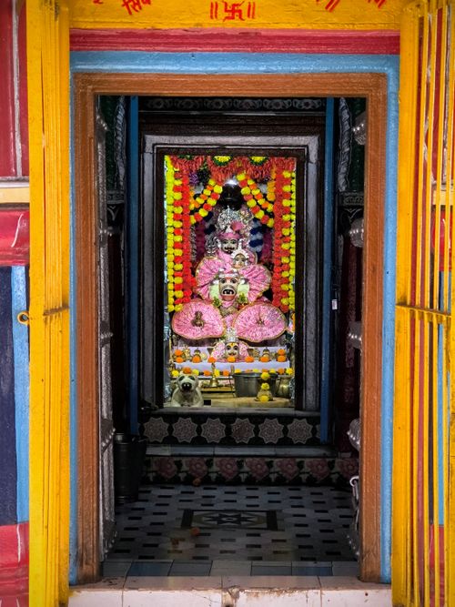 Free Vibrant view inside a Hindu temple featuring a decorated Shiva statue, adorned with flowers. Stock Photo