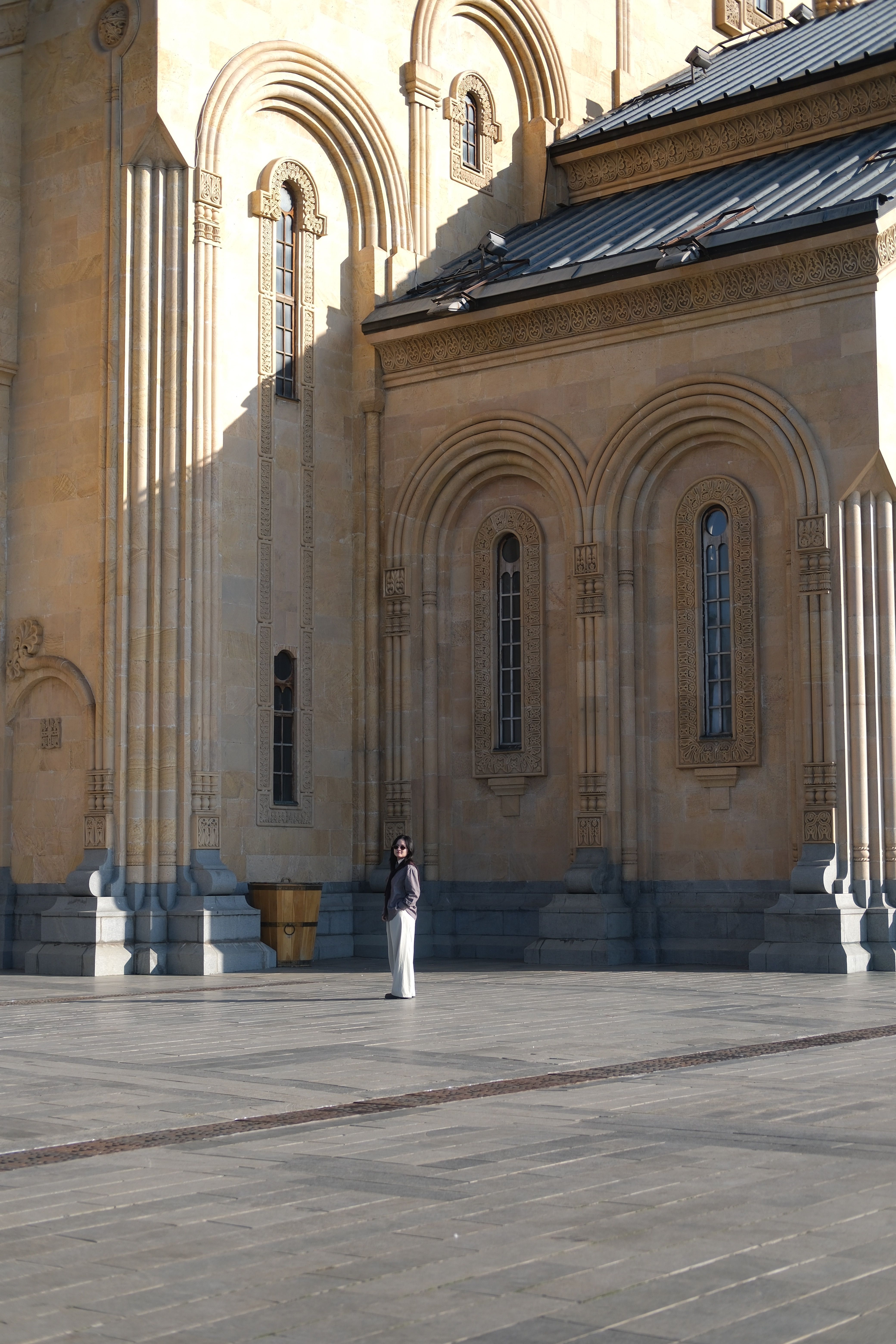 A person stands alone by a large, ornate structure, highlighting its grandeur.