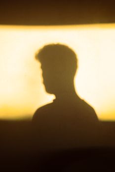 A silhouette of a person cast against a glowing golden background, creating a mysterious and artistic vibe.