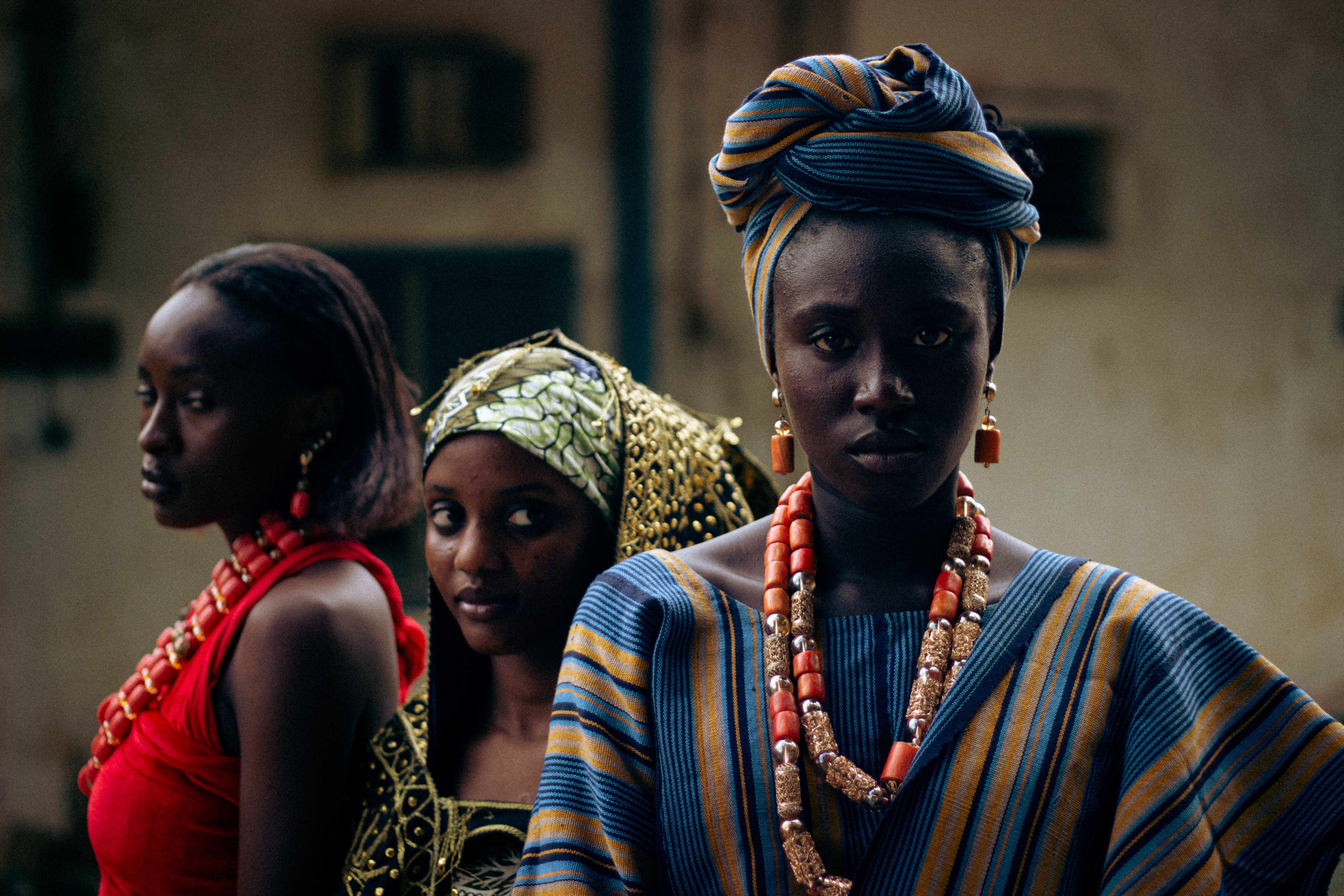 Portrait of three women in vibrant African attire and jewelry, showcasing cultural heritage.