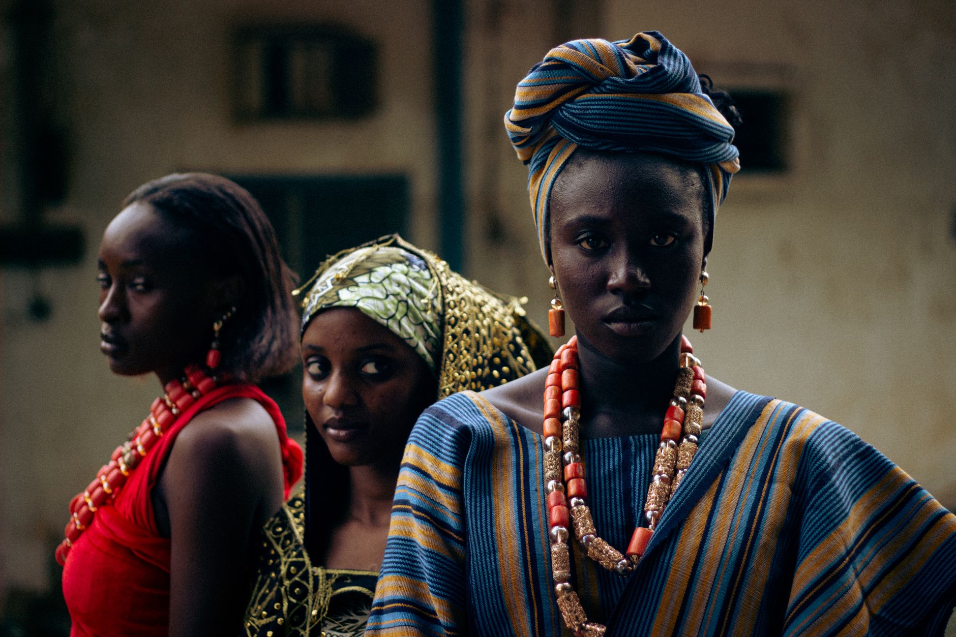 Portrait of three women in vibrant African attire and jewelry, showcasing cultural heritage.