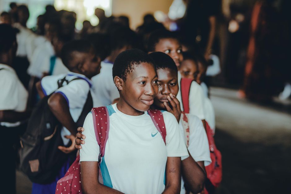 Close-up of students in school uniforms and backpacks indoors. Diverse and educational setting.