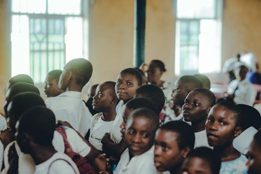 A diverse group of students attentively participating in an indoor school assembly.