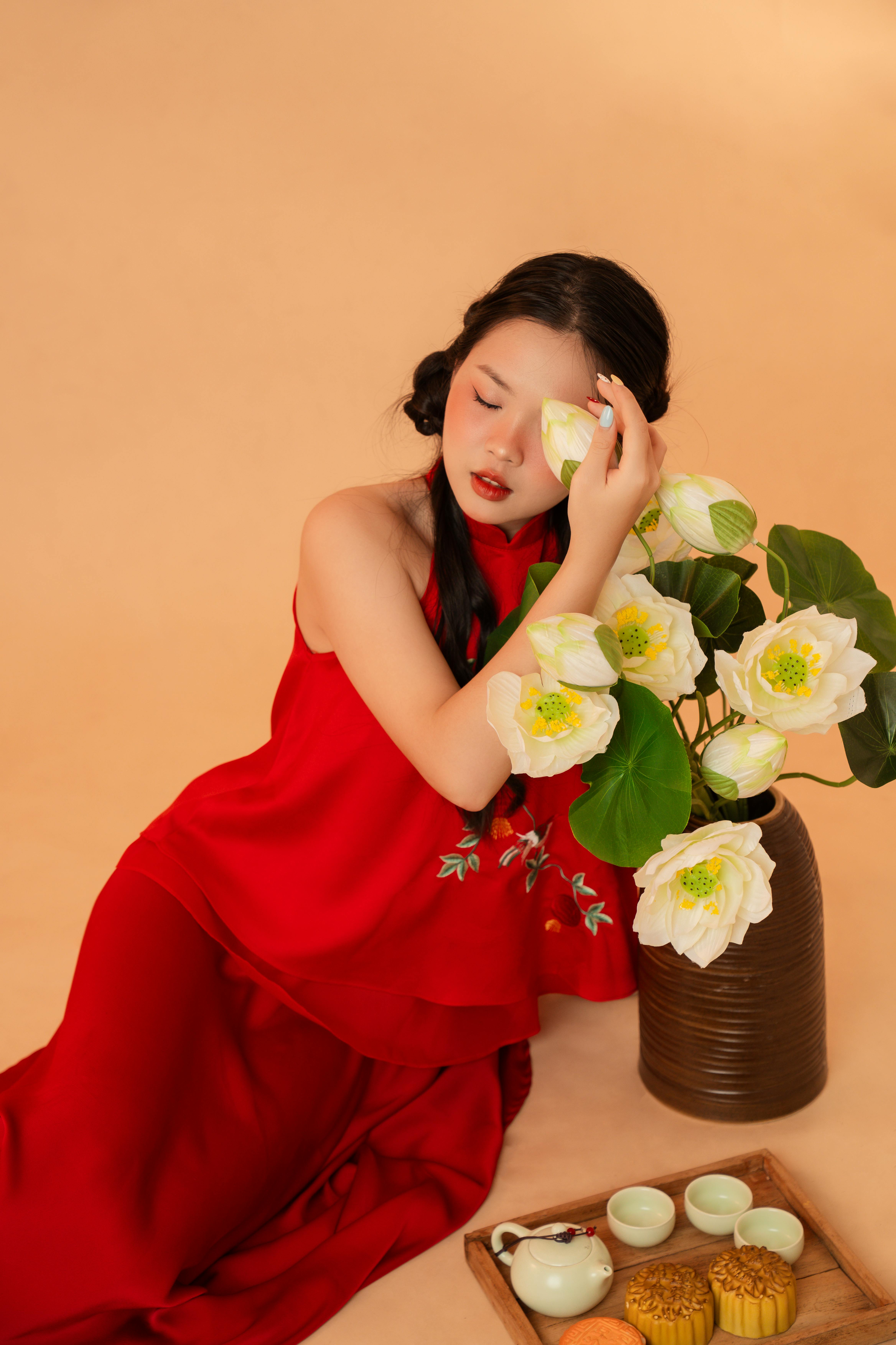 红衣女子优雅地与荷花和茶具摆出姿势，营造出宁静而充满活力的景象