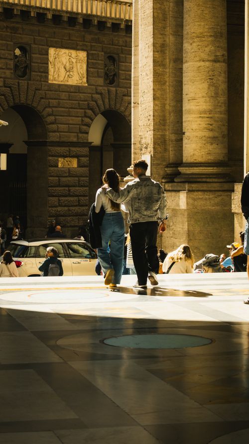 Free A romantic couple walking together amidst iconic European architecture in warm sunlight. Stock Photo