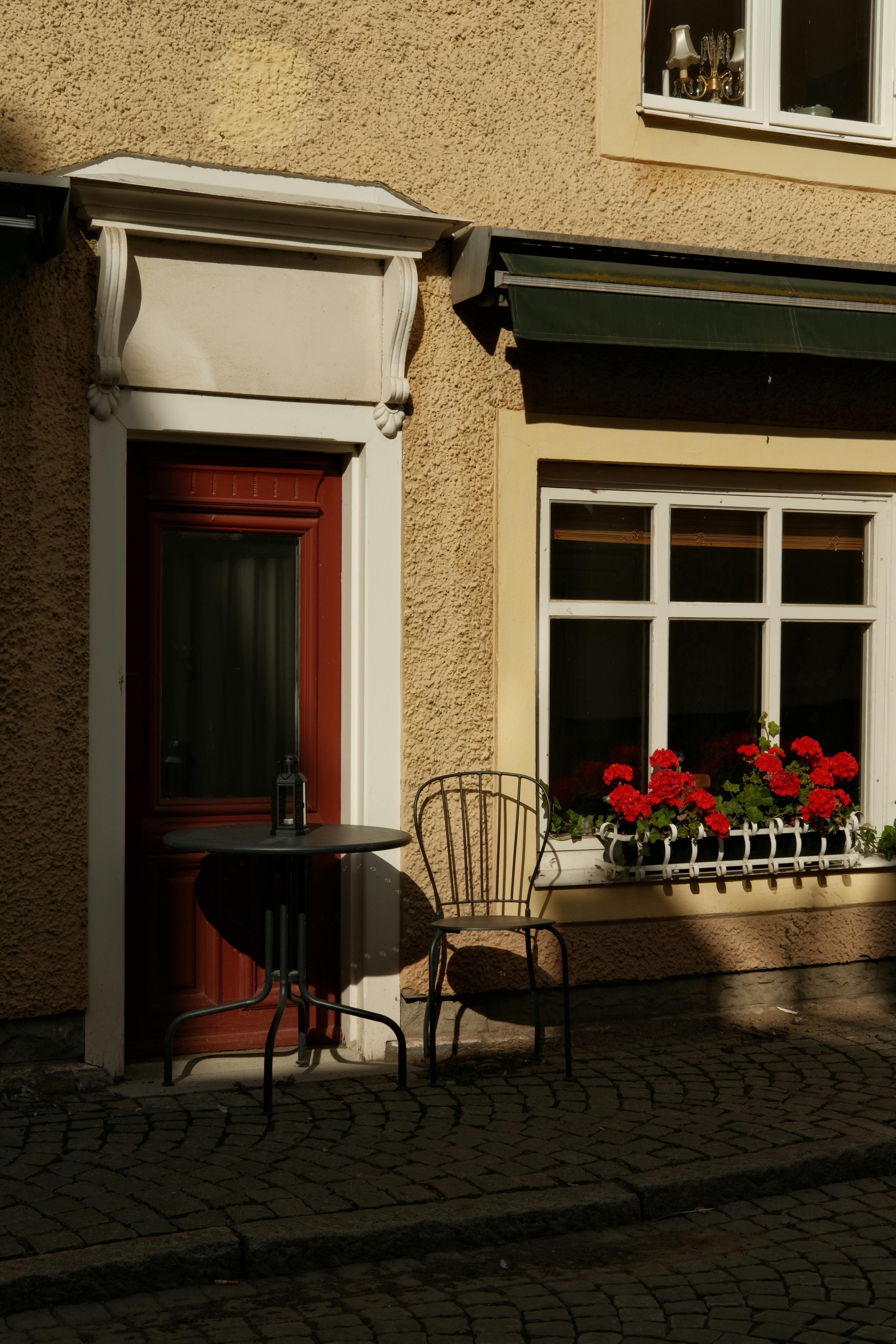 Cozy outdoor seating area with red door and flowers, perfect for a peaceful retreat.