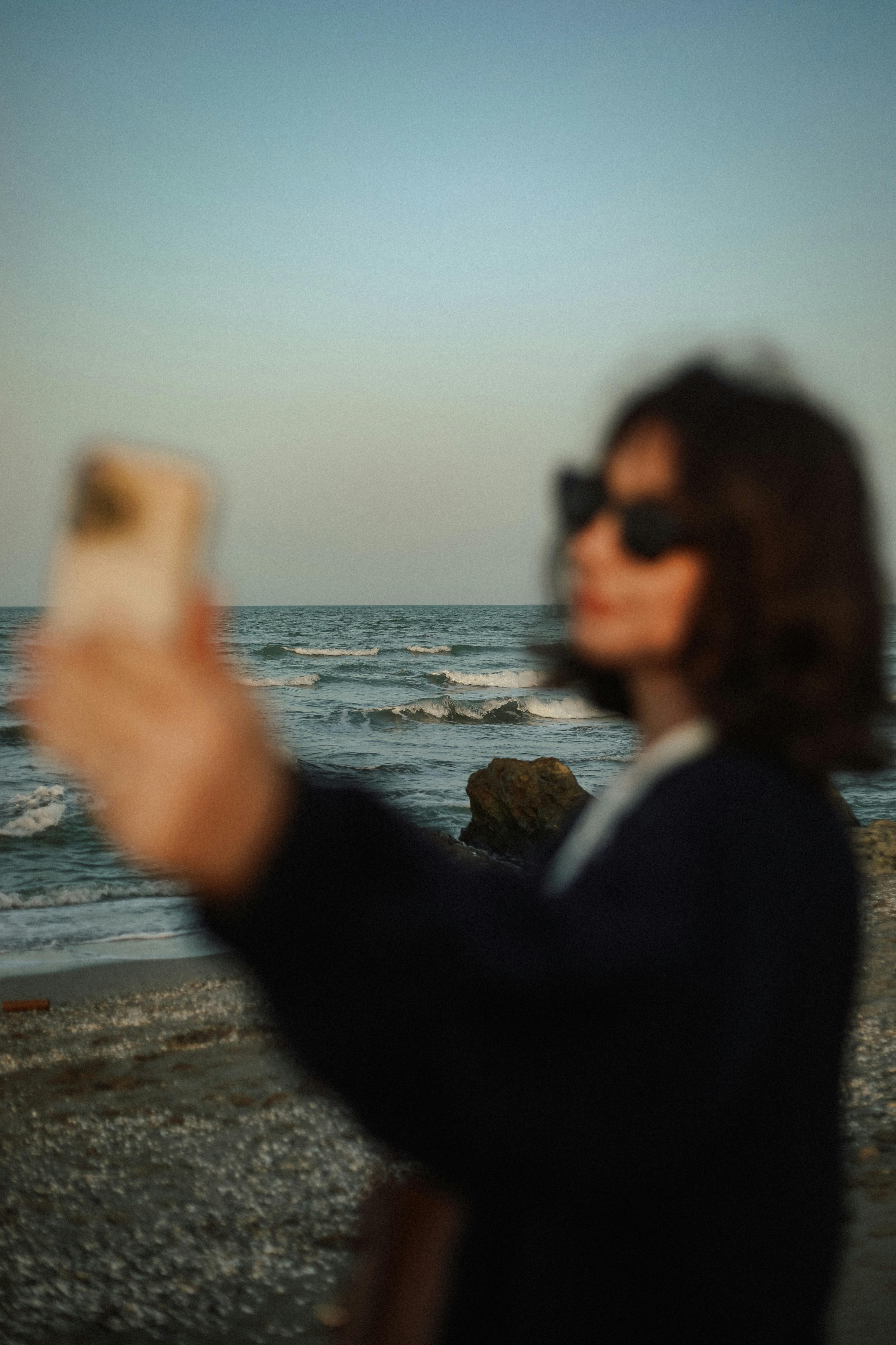 Free A fashionable young woman takes a selfie by the sea at sunset in Baku, capturing the vibrant and relaxed atmosphere. Stock Photo