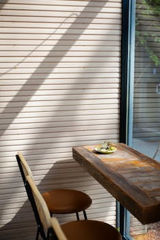 A warm and inviting coffee shop corner with sunlit wooden table and chairs, perfect for a quiet moment.
