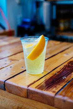 A vibrant non-alcoholic sparkling water with an orange slice on a rustic wooden table.
