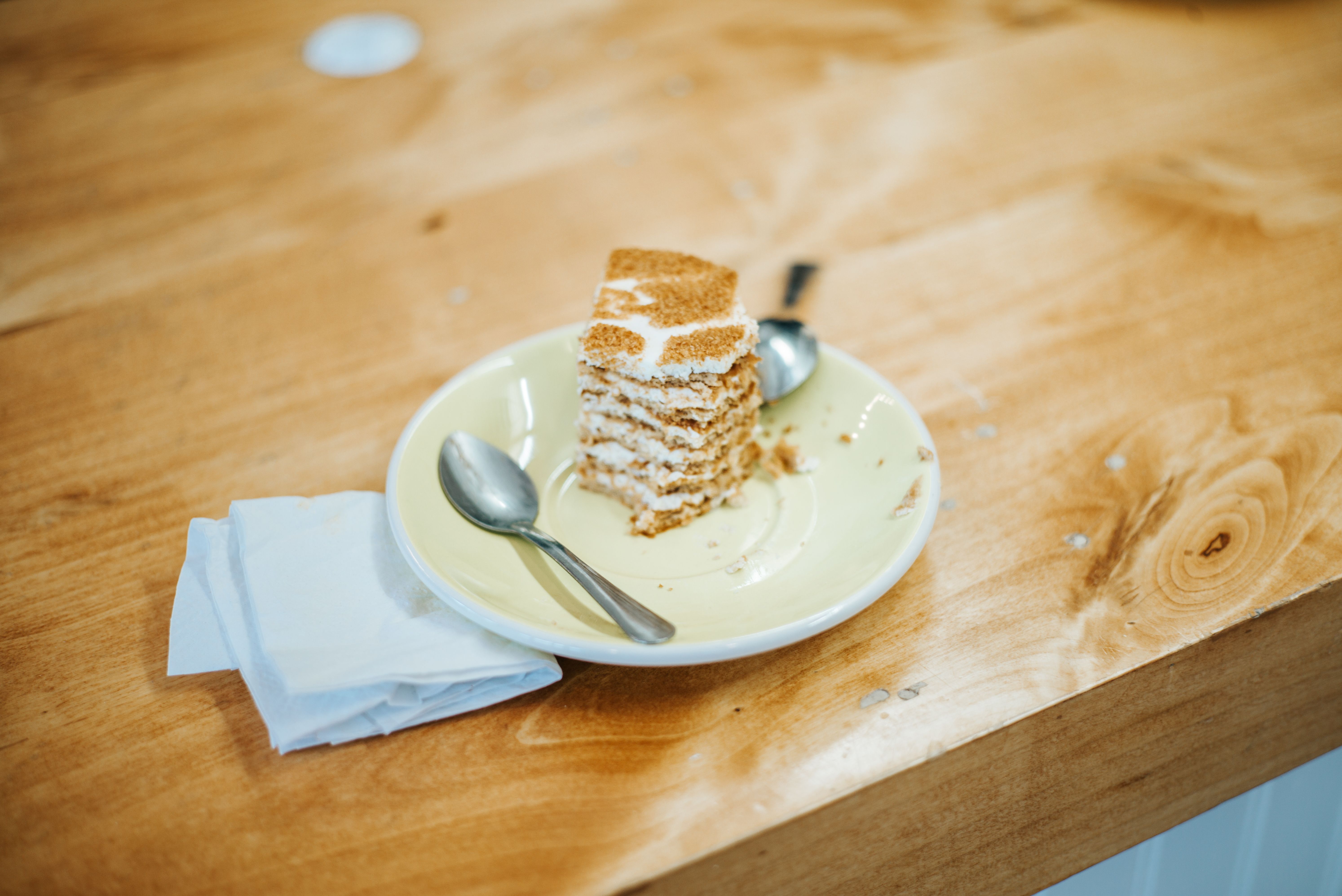 Close-up of a slice of layered cake with utensils on a wooden table, perfect for food and lifestyle concepts.