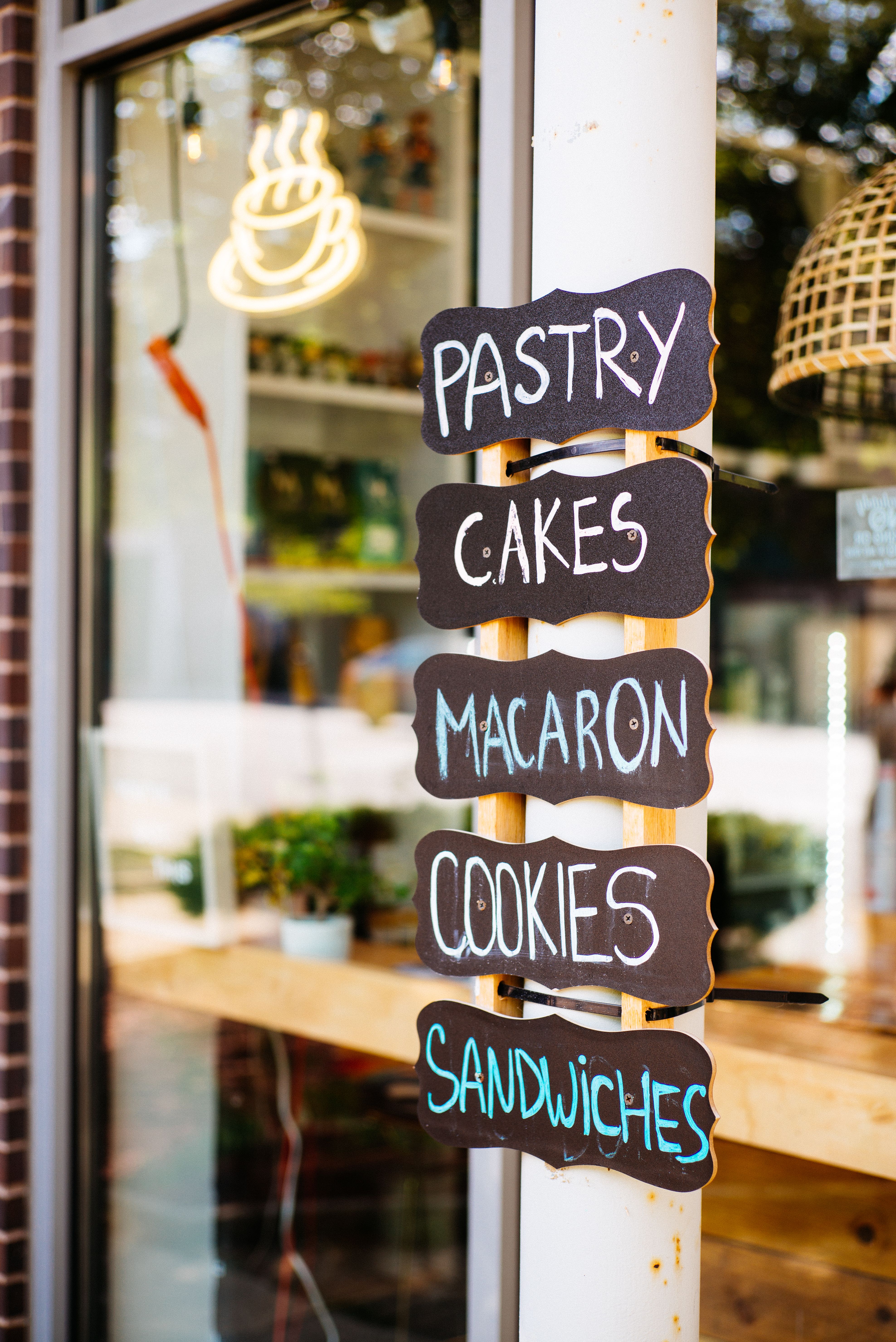 A vibrant bakery sign showcases pastry and cakes outside a cozy cafe.