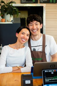 Happy baristas posing at a coffee shop counter, radiating warm hospitality and charm.