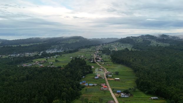 Scenic aerial landscape of a verdant valley with forests and fields in Nepal, under a cloudy sky.