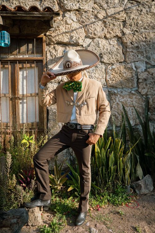 Free A person in traditional Mexican attire standing by a rustic wall, embodying cultural heritage and style. Stock Photo