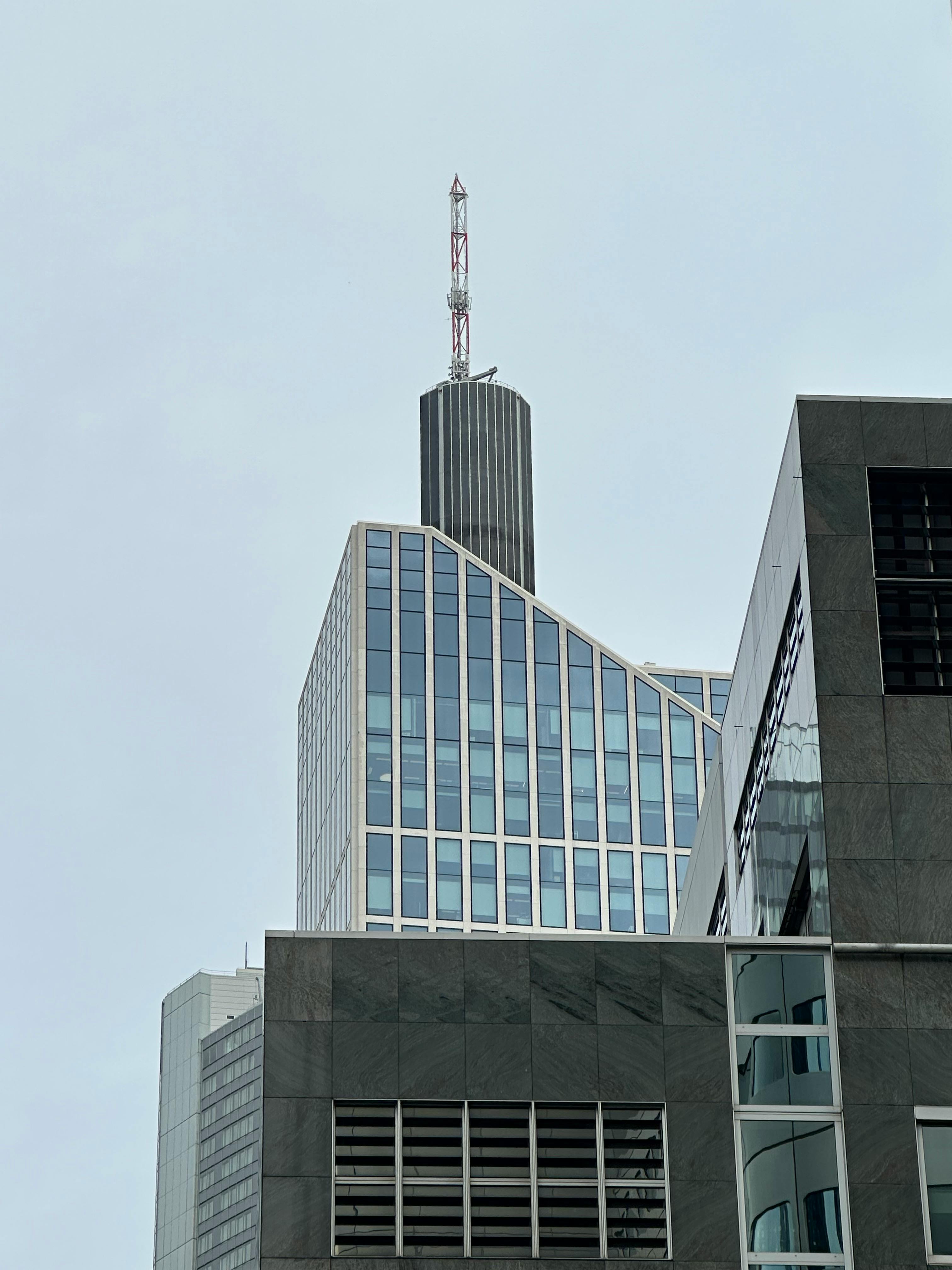 免費 一座引人注目的現代摩天大樓，在多雲的天空下呈現出獨特的幾何設計。 圖庫相片