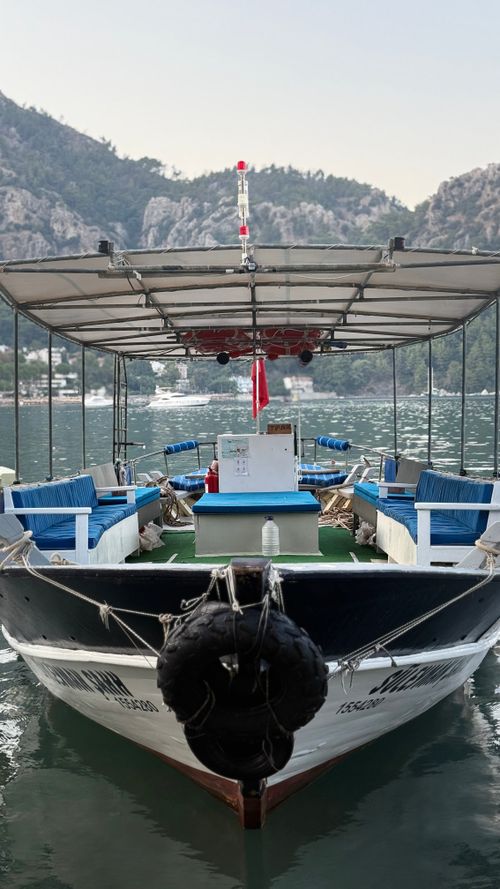 Free Front view of a boat docked on a tranquil mountain lake surrounded by scenic hills. Stock Photo