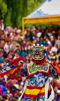 Colorful masked dancer performing at a lively outdoor cultural festival.