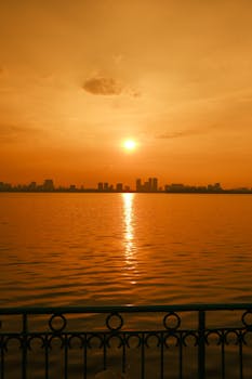 Stunning sunset view across a water body with city skyline in Japan, reflecting golden hues.