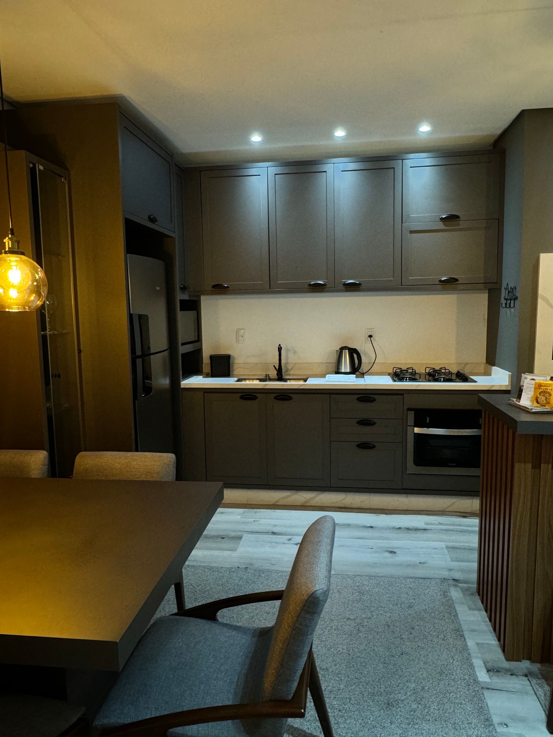Contemporary kitchen and dining area with cozy illumination, pale furnishings and sleek cabinetry