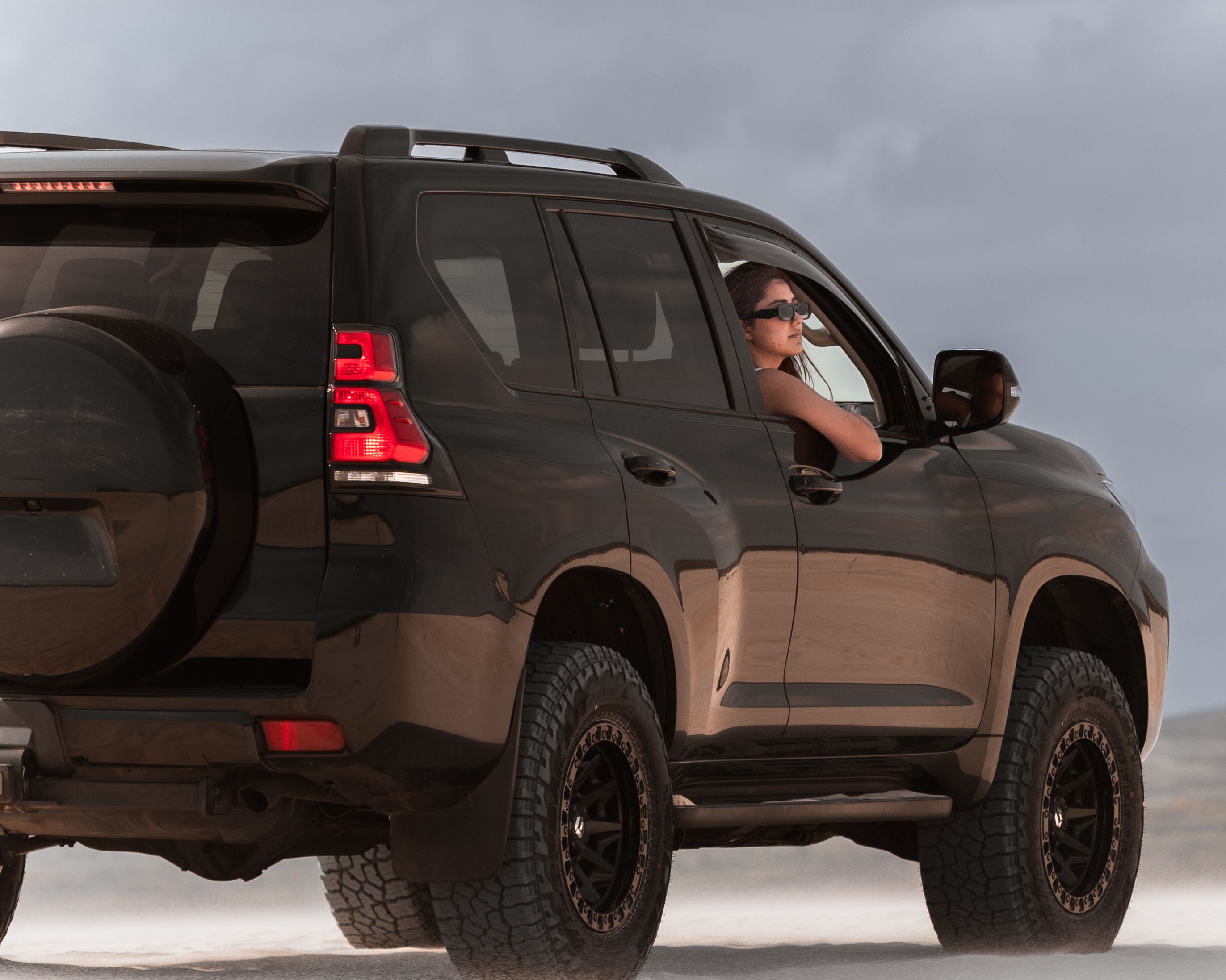 A woman enjoys an off-road experience in a rugged SUV in Australia's sand dunes.