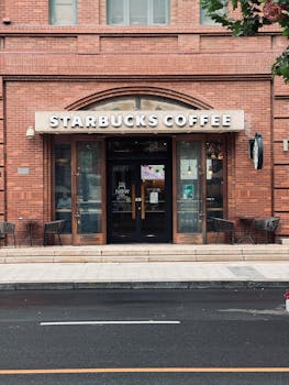 Classic brick facade of a Starbucks coffee shop with seating outside, seen on a city street.