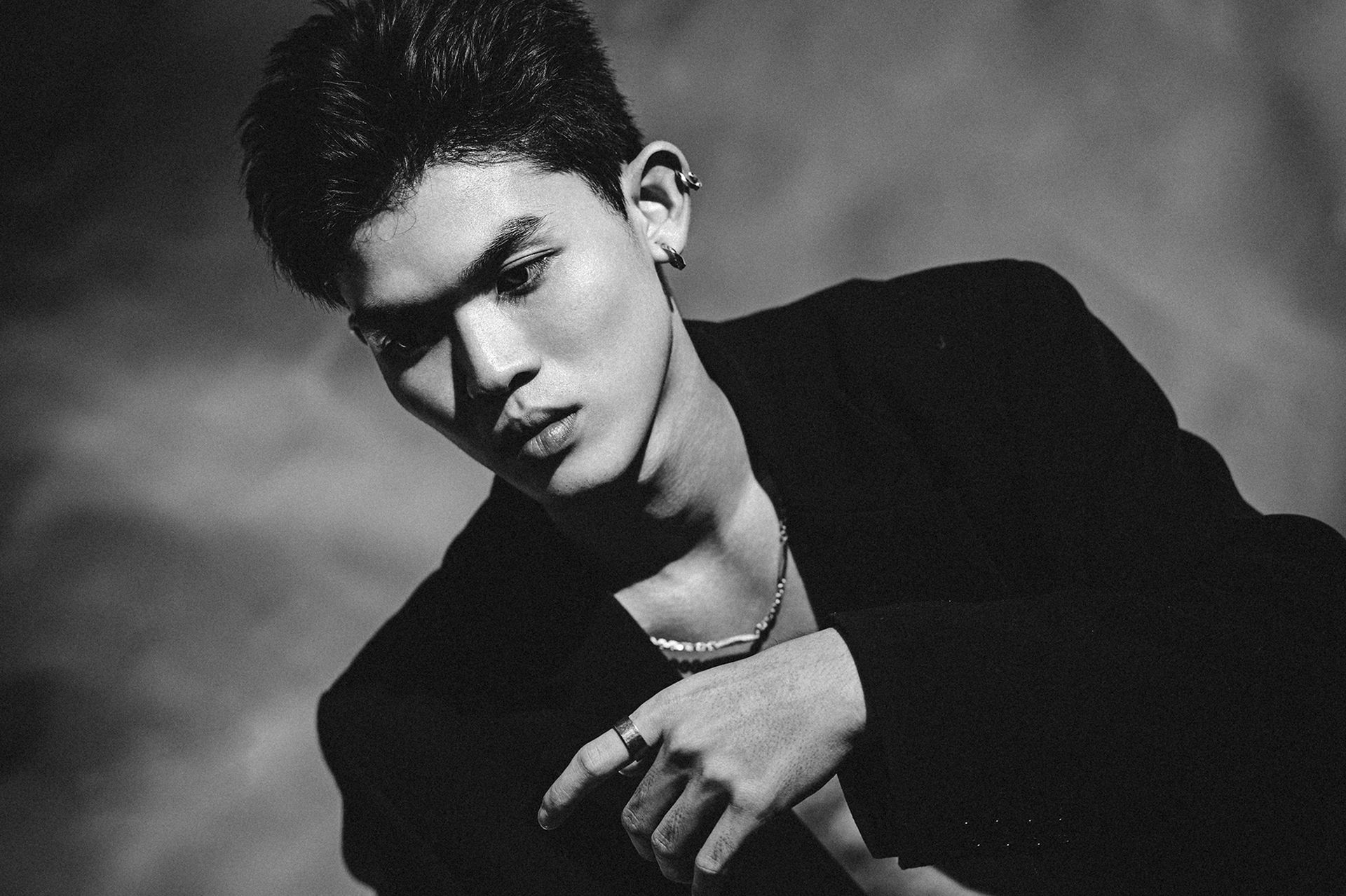 Dramatic black and white portrait of a young man with a contemplative gaze.