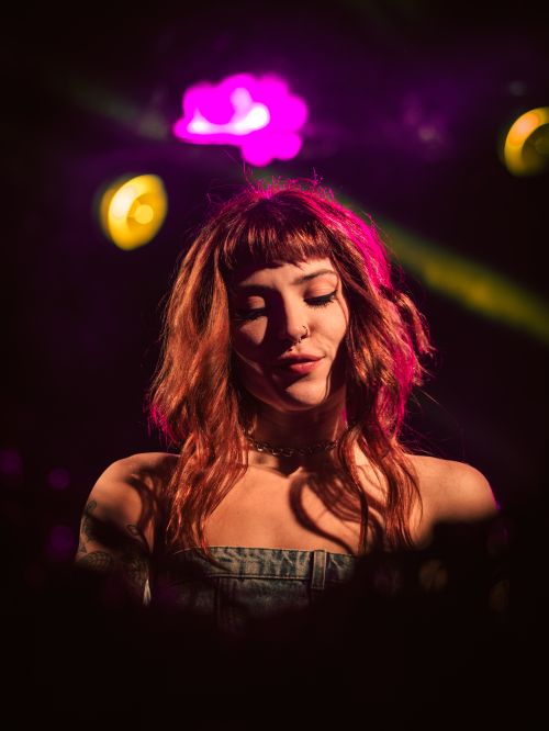 Free A female DJ immersed in a vibrant light show, creating an engaging club atmosphere. Stock Photo