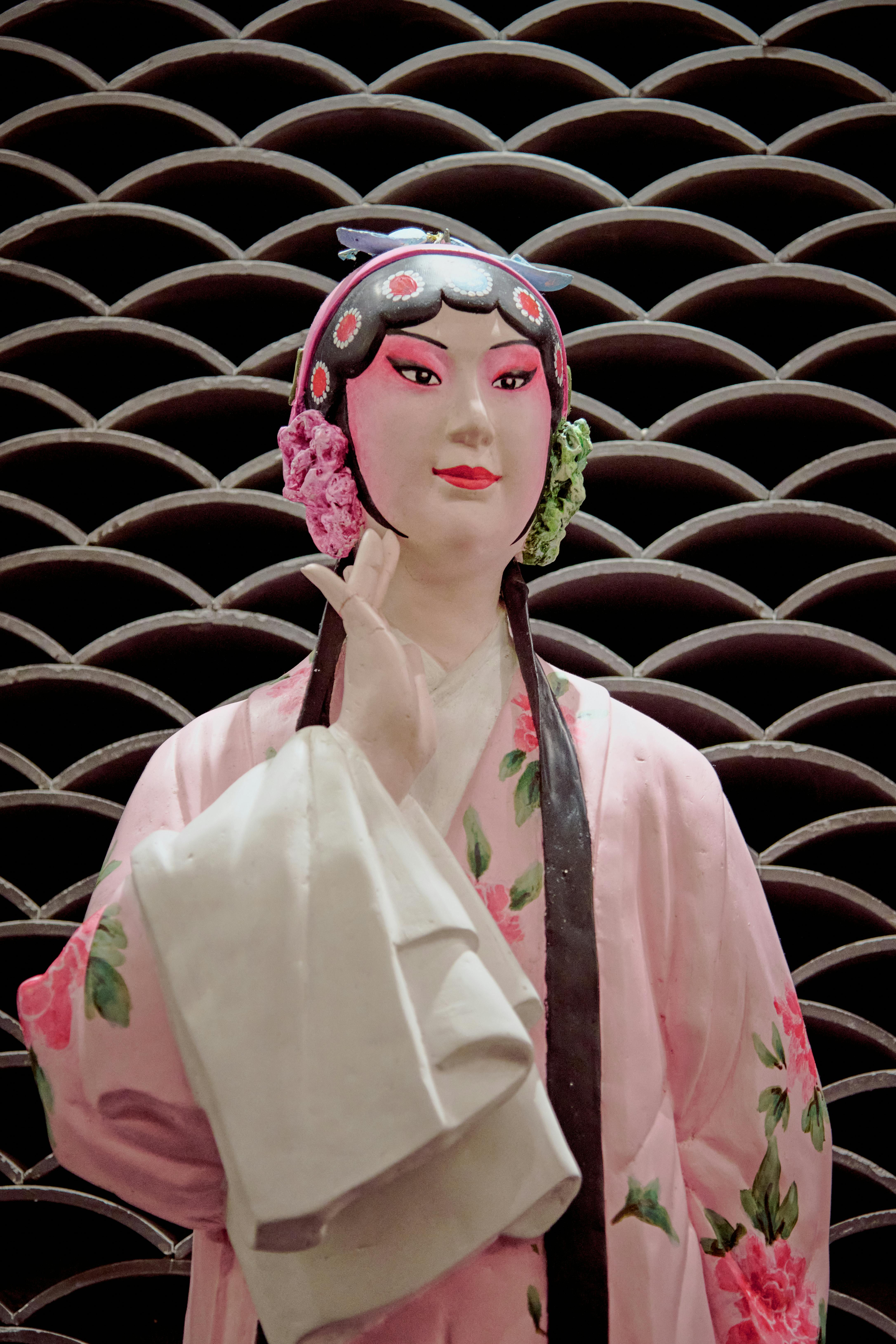 ฟรี ตุ๊กตาเอเชียสีสันสดใสสวมชุดลายดอกไม้พร้อมพื้นหลังอันสวยงาม คลังภาพถ่าย