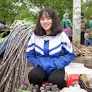 一位开朗的年轻女子坐在越南拉才的一个市场上，周围都是甘蔗茎