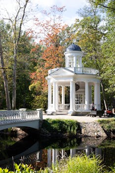 Elegant white pavilion by a pond in Jūrmala, Latvia, amidst autumn foliage.