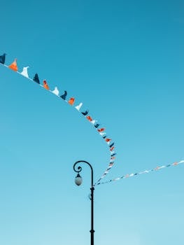 Colorful pennant flags curve gracefully against a clear blue sky, creating a vibrant visual.