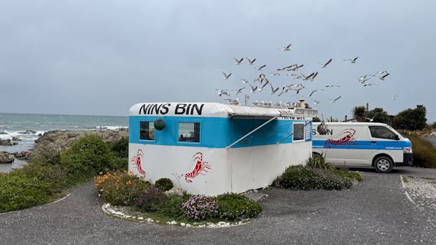 Seaside crab shack "Nins Bin" with seagulls and ocean backdrop.