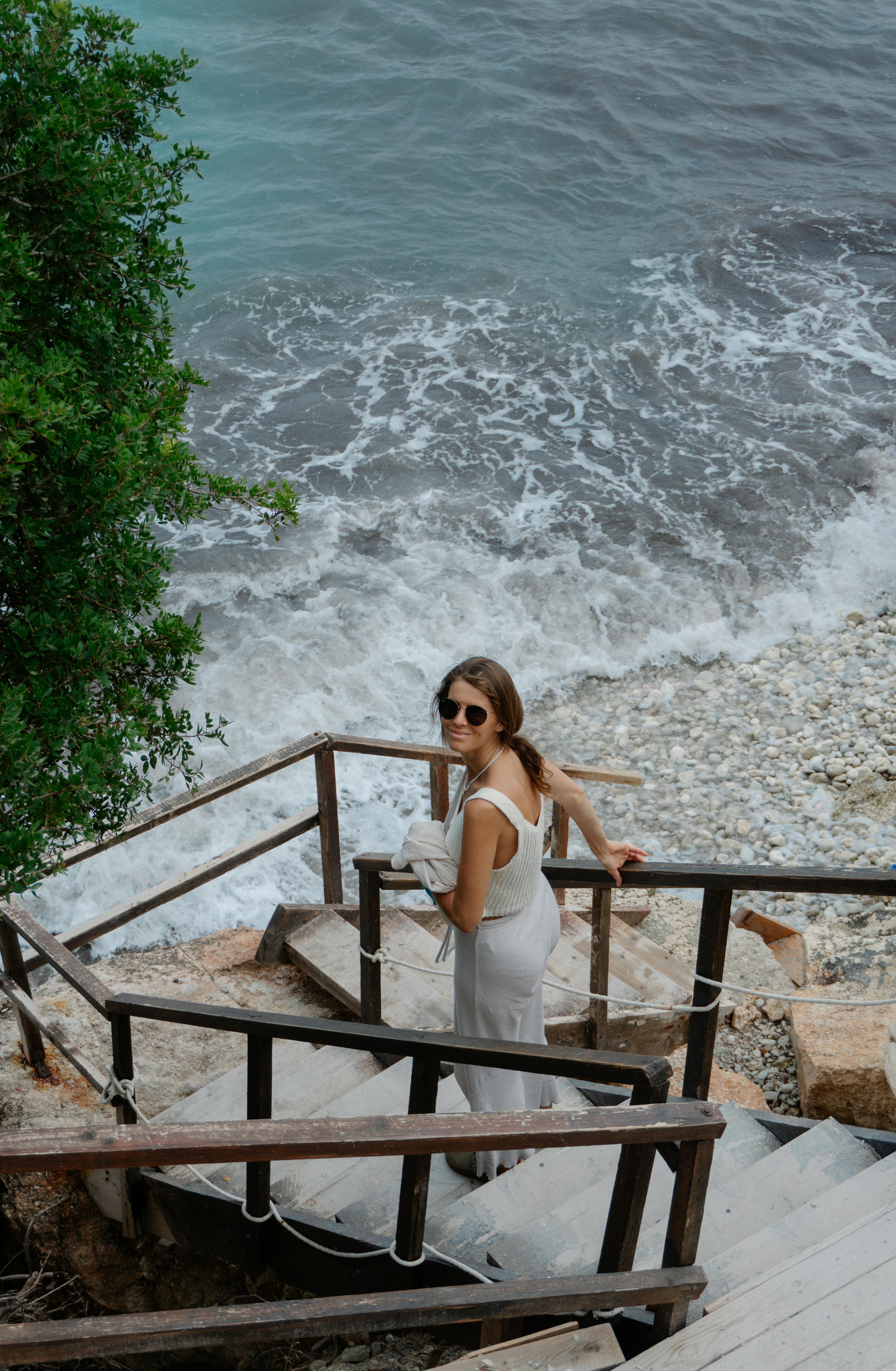 身穿白色连衣裙的女子，从海边台阶上走下