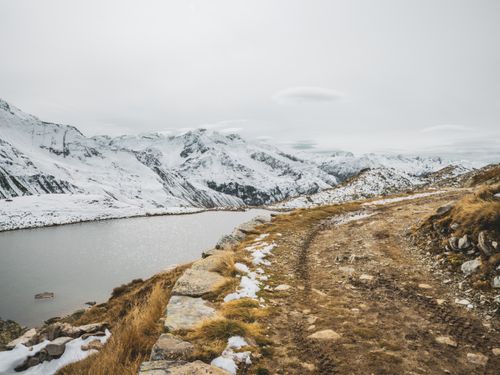 Free Discover the serene winter beauty of Andermatt's snowy mountains and tranquil lake. Stock Photo