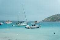 在希腊扎金索斯清澈水域中，停泊的船只展现出宁静景色