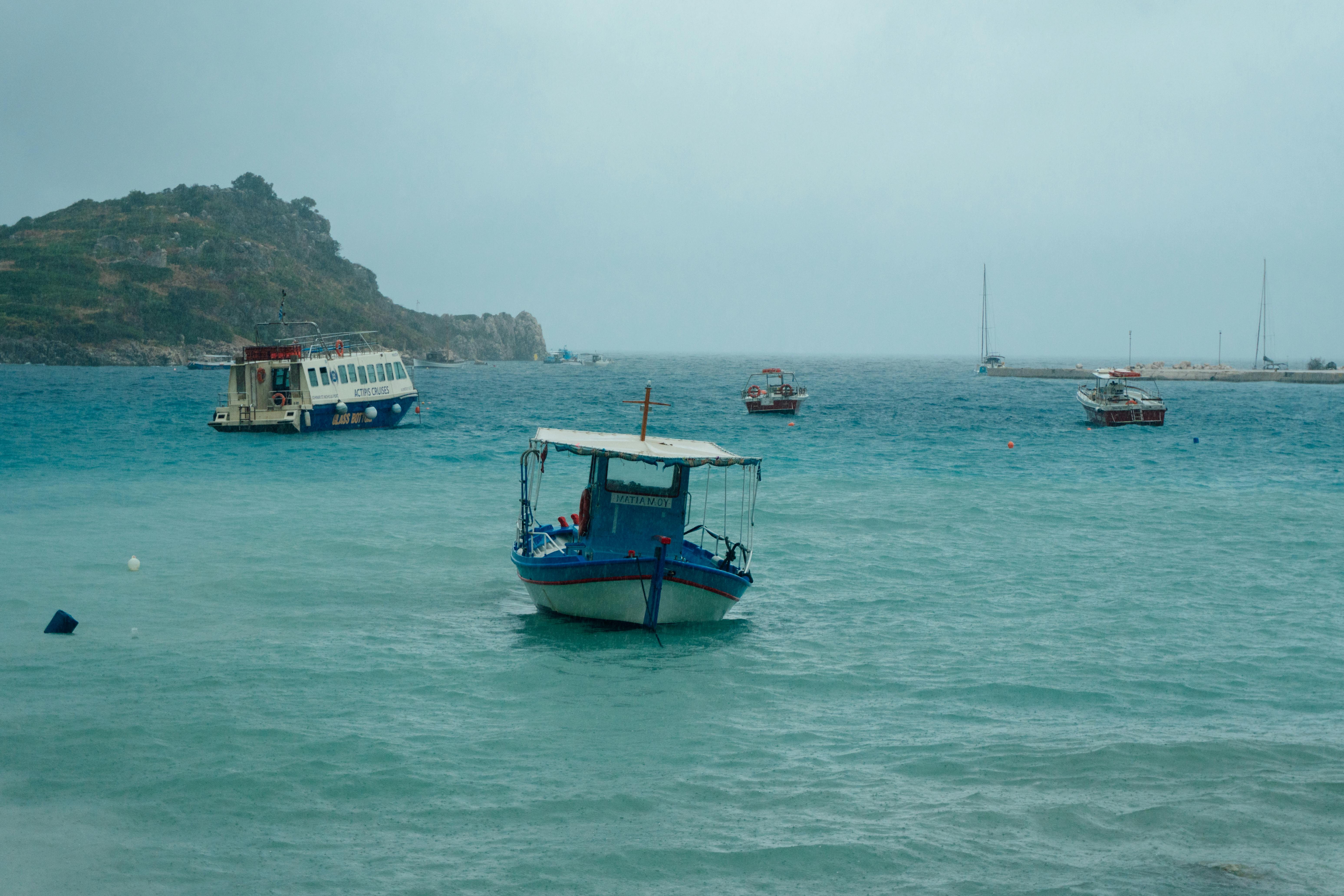 小船停泊在希腊扎金索斯海岸的清澈蓝色水域中
