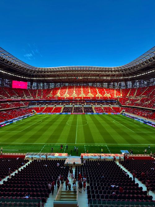 Free Expansive view of a modern stadium filled with fans under a clear blue sky. Stock Photo