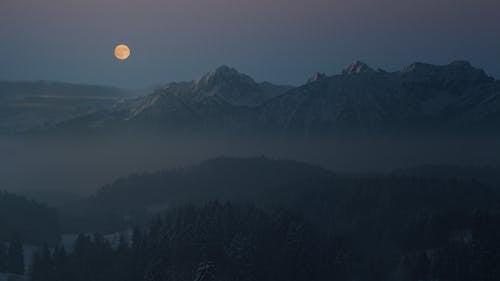 Silhouette De Montagnes Couvertes De Brouillard Léger Sous La Pleine Lune