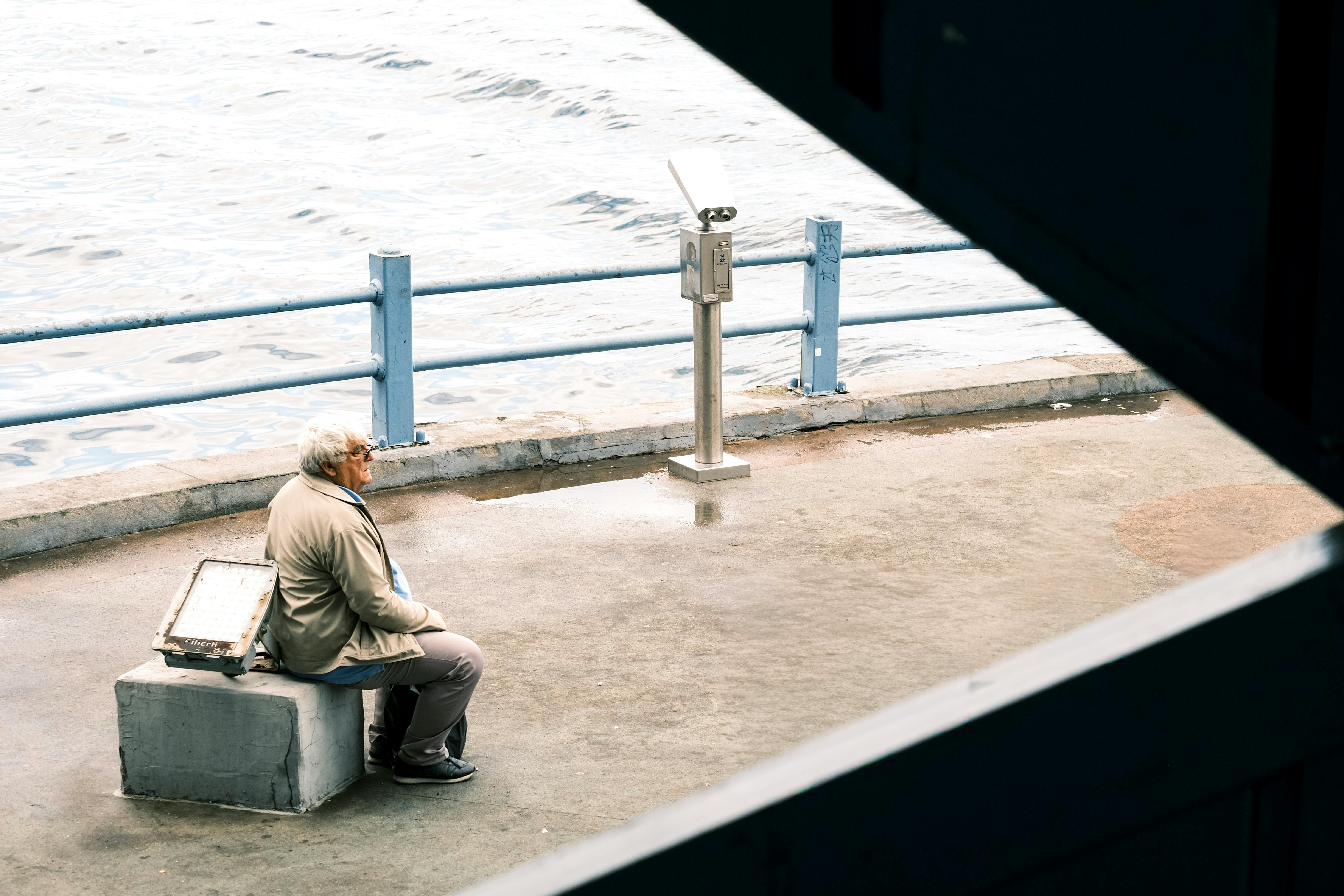 一位老年人独自坐在海滨的长凳上，在海边沉思