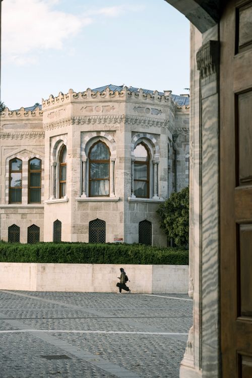 Free Capture of a person walking near a historic European building with intricate architecture. Stock Photo