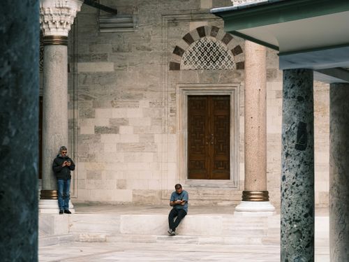 Free Two men using smartphones outside a historic building with ornate architecture. Stock Photo
