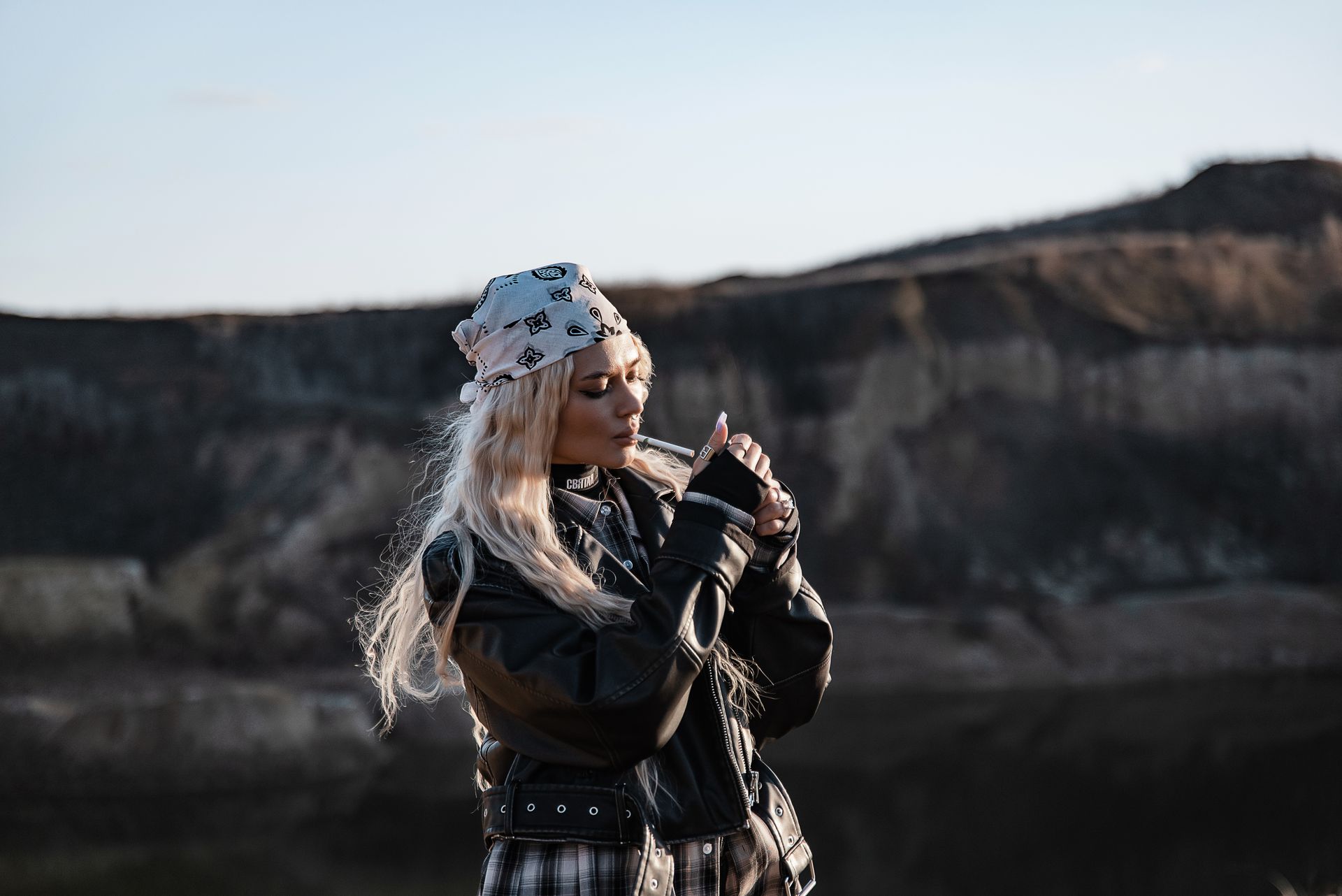 A fashionable woman wearing a bandana and leather jacket in an outdoor setting.