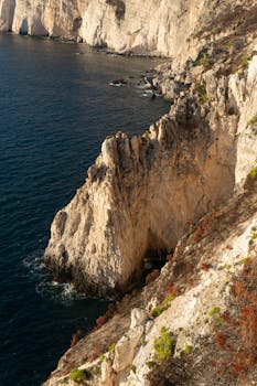 日落时，悬崖的壮丽景色映入眼帘，崎岖的岩石结构与深蓝色的大海交相辉映