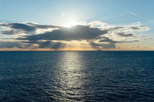 Free Beautiful ocean view at sunset with dramatic clouds and sun rays over the water. Stock Photo