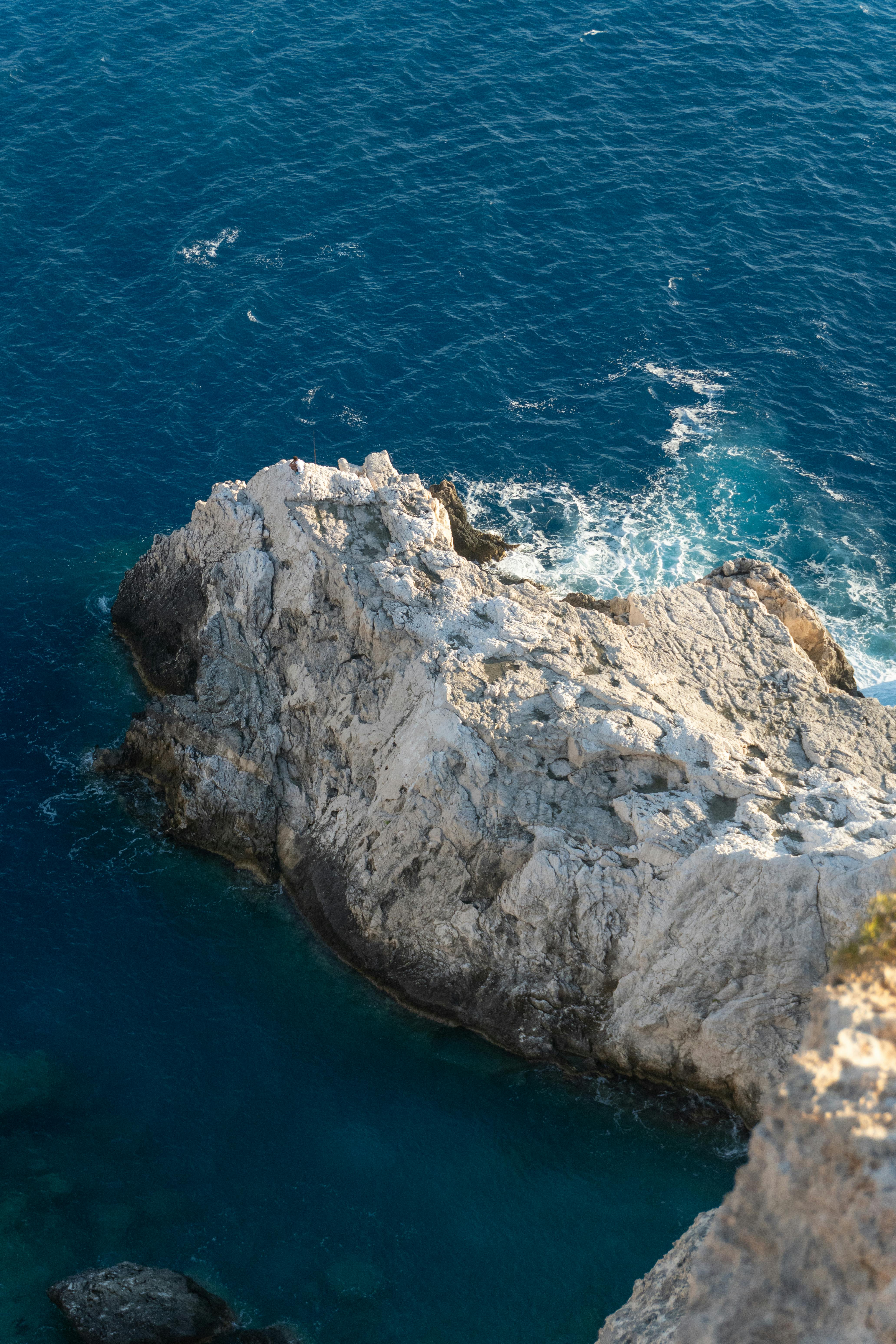 鸟瞰崎岖的海岸岩石，与充满活力的蓝色海浪